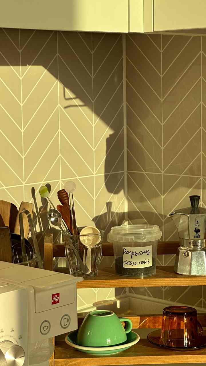 温かみのあるウッドトーンのキッチン、モカポットやコーヒーマシーン、マグカップが配置された雰囲気のあるホームカフェ空間