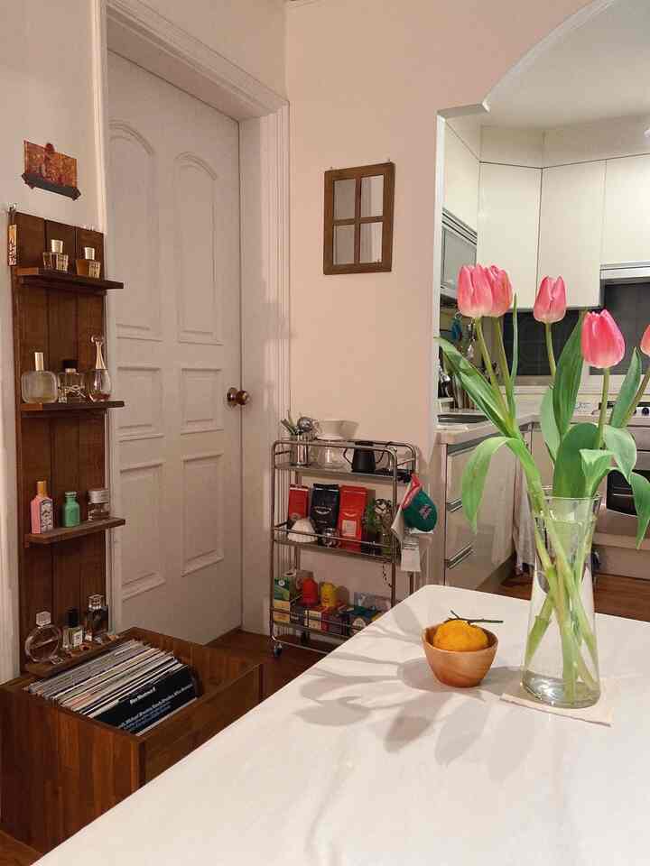 白と木目調の調和が美しいキッチン、白いテーブルクロスが掛かったテーブルにピンクのチューリップが置かれた温かみのある空間