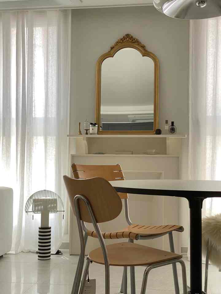 白とベージュ調のリビング、ゴールドフレームのヴィンテージミラーと白い暖炉が配されたフレンチカントリーの雰囲気あるインテリア