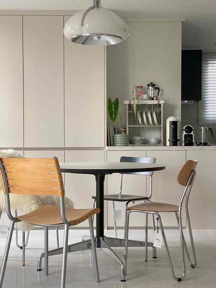 ホワイトとライトブラウンの色調のキッチンとダイニングスペース、円形ダイニングテーブルと椅子が調和したモダンなおうちカフェ空間