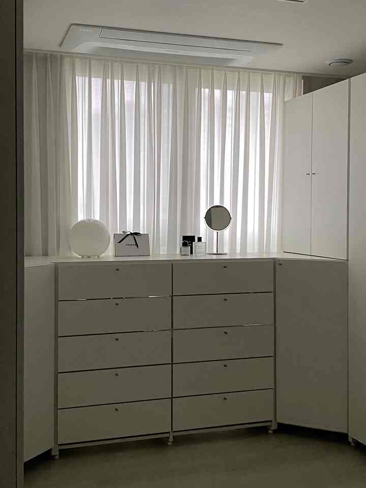 白を基調としたウォークインクローゼット、複数のチェストとコーナー収納が配置された清潔感のあるモダンなインテリア