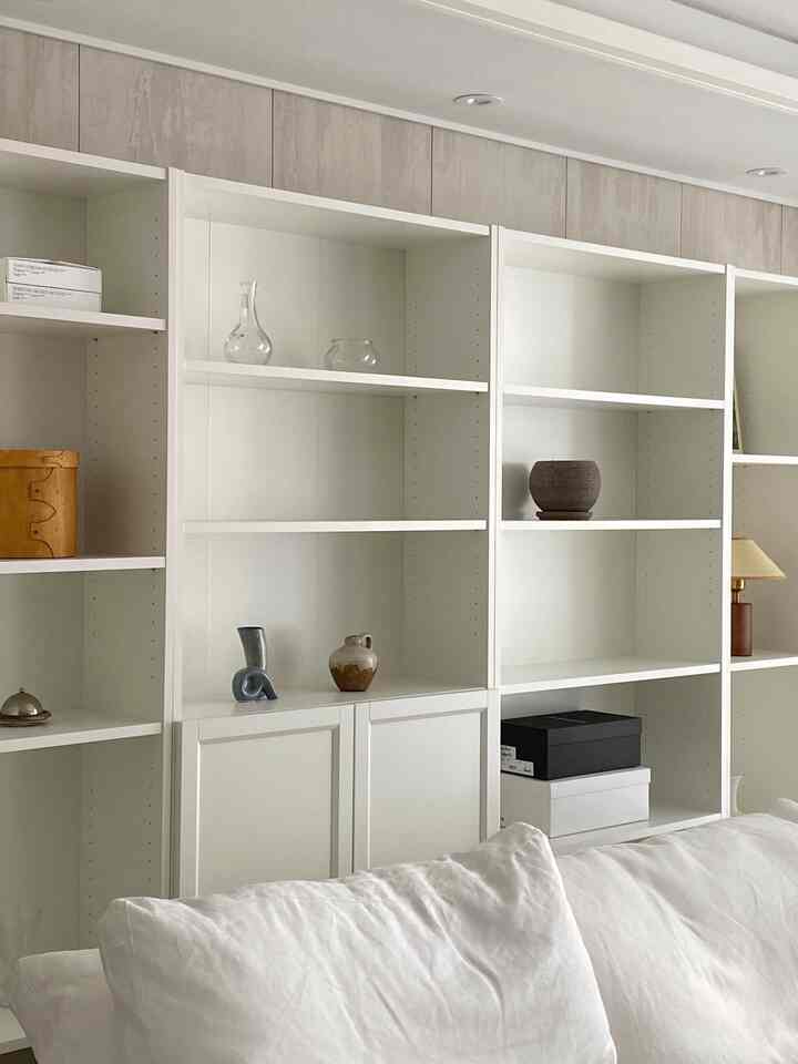 白とナチュラルトーンのリビングルーム、複数の本棚と白いソファが配置され、すっきりとしたモダンな雰囲気のインテリア