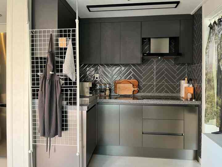 グレー調のキッチンスペース、黒白のセラミックタイルの壁とステンレス製のカウンターが調和したモダンな雰囲気