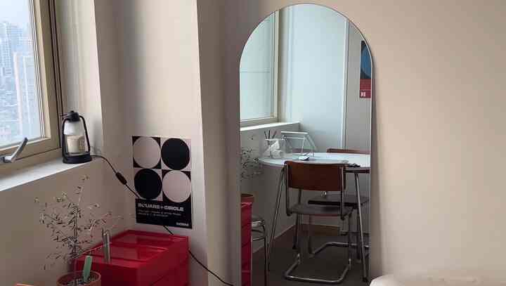 ナチュラルカラーのコンパクトな部屋にフレームレスのアーチ型全身鏡とダイニングチェアが配置されたシンプルなインテリア