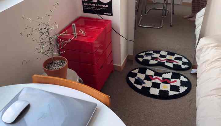 白と赤が調和するワンルームの空間、ミッドセンチュリーモダンのダイニングテーブルと赤いトロリーが配置されたコンパクトで居心地の良いインテリア