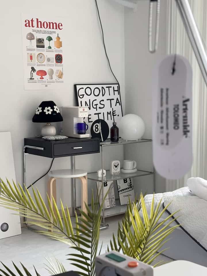 白とグレーのトーンのリビング、サイドテーブルや植物、額が配置されたシンプルでモダンなインテリア