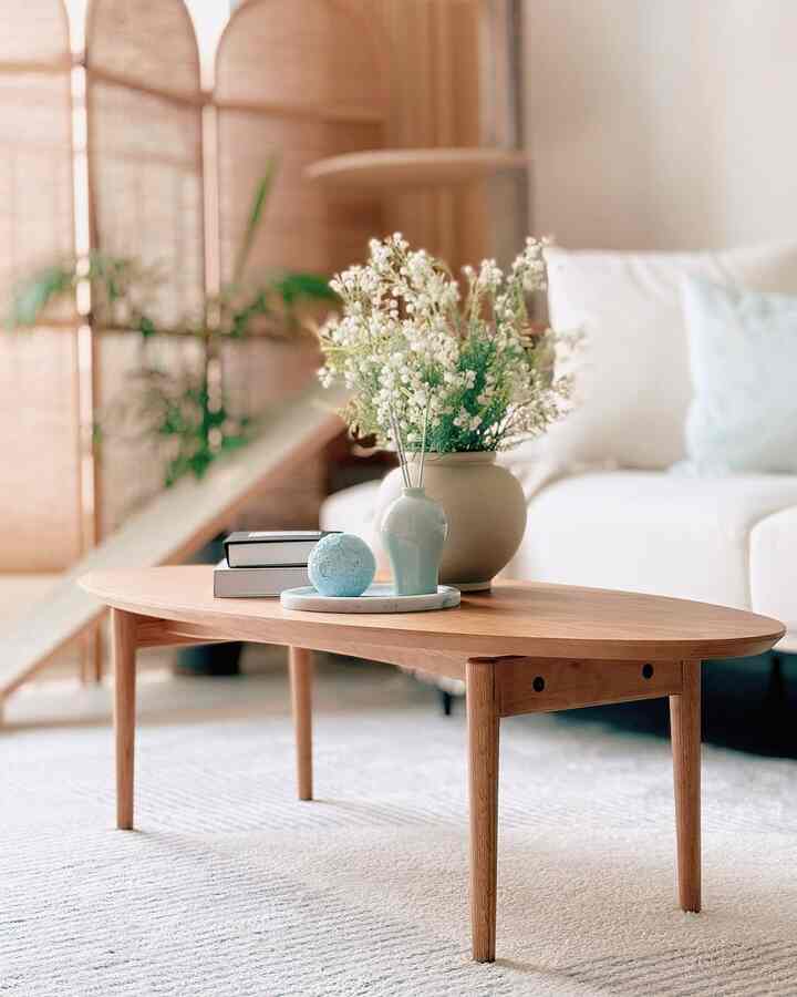 ナチュラルな色調のリビング、木製コーヒーテーブルと白いソファ、カスミソウの花瓶が置かれた落ち着いたインテリア