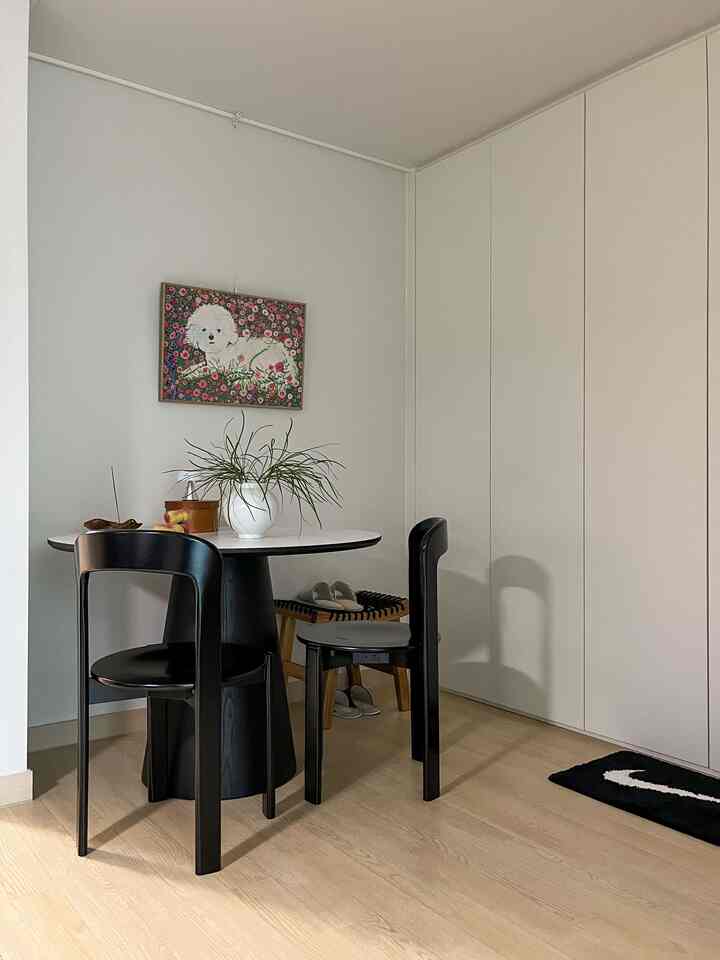 白い壁とクローゼット、ライトウッドの床が調和したダイニングルーム。丸いダイニングテーブルと黒い椅子が配置された雰囲気のある空間