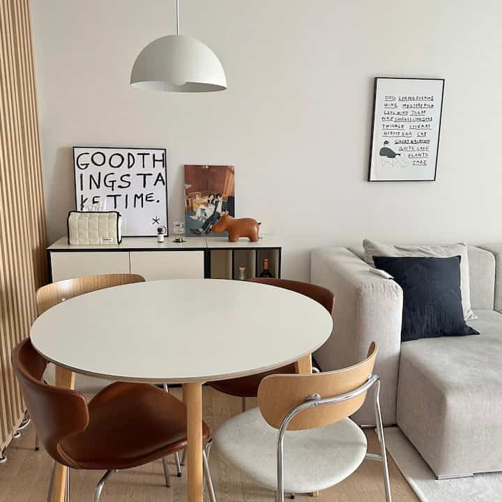 温かみのあるアイボリー色の壁とモジュラー収納、丸いダイニングテーブルと椅子が配置されたモダンでナチュラルなダイニングルーム