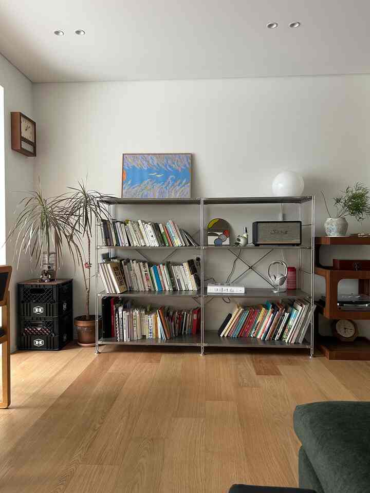 ナチュラルカラーのリビング、ステンレス棚とラワン合板家具が調和した印象的な空間