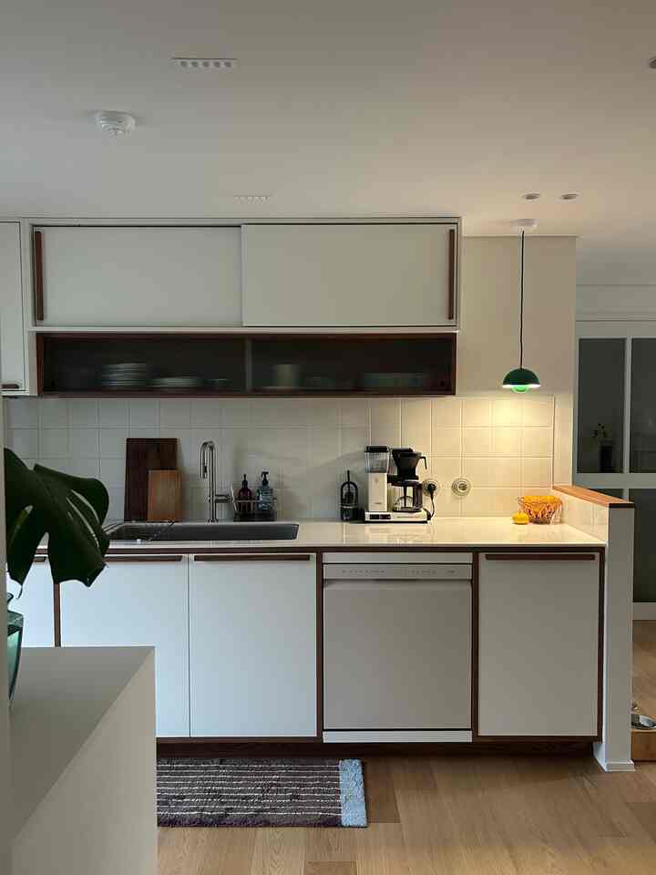 白と木目調のミニマルなキッチン、コーヒーマシンとペンダントライトが印象的な空間