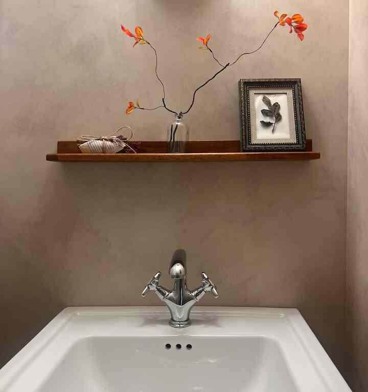 ブラウンの木目調棚と白い洗面台が配置されたシンプルでクラシックなバスルーム