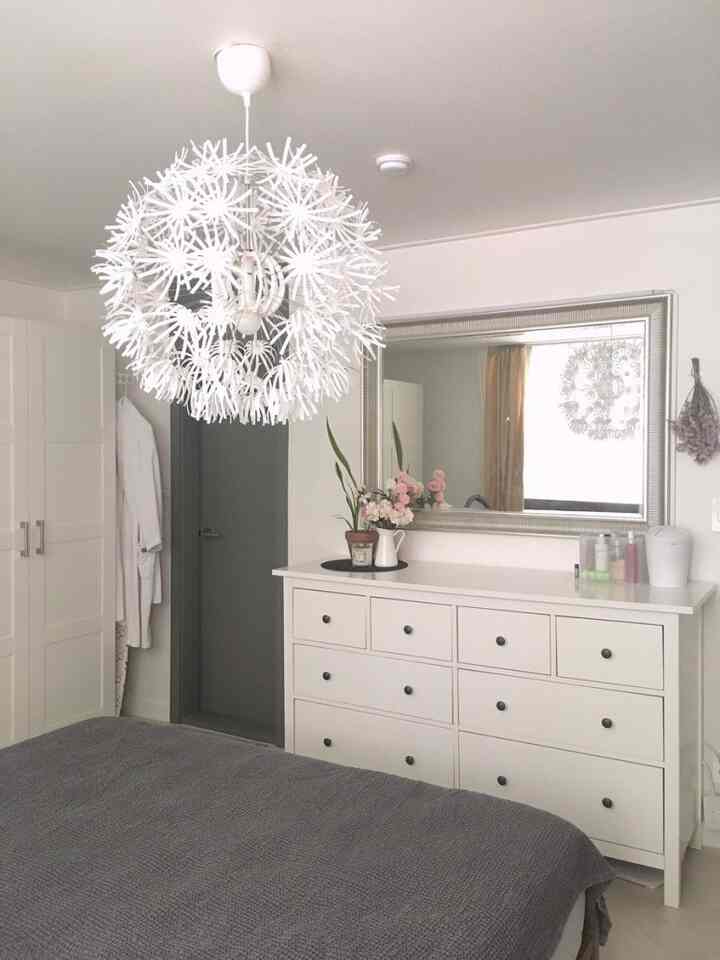 A white and gray toned bedroom featuring a large mirror and dresser, creating a calm and neat atmosphere