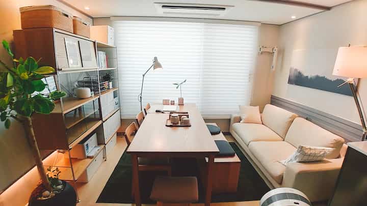 Natural wood tones and beige furniture in a living room cum study featuring a home cafe atmosphere with cozy ambiance