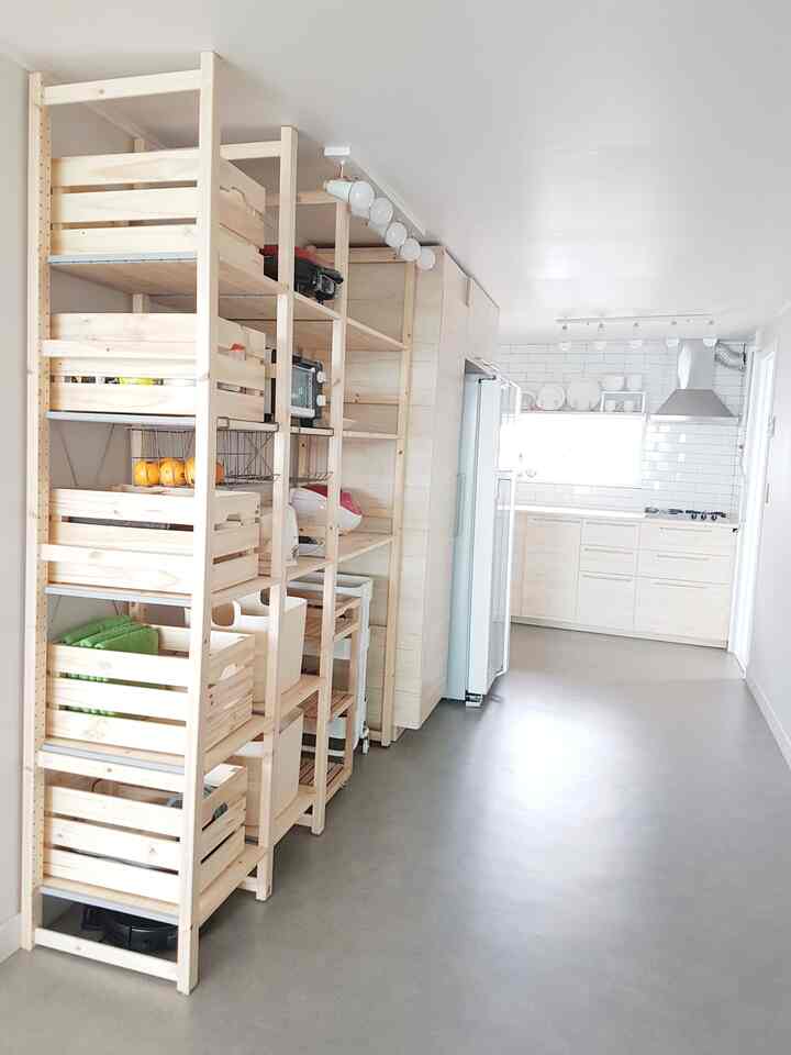 ナチュラルな色調のキッチンスペース、木製の棚と収納が整然と配置された明るく実用的なインテリア