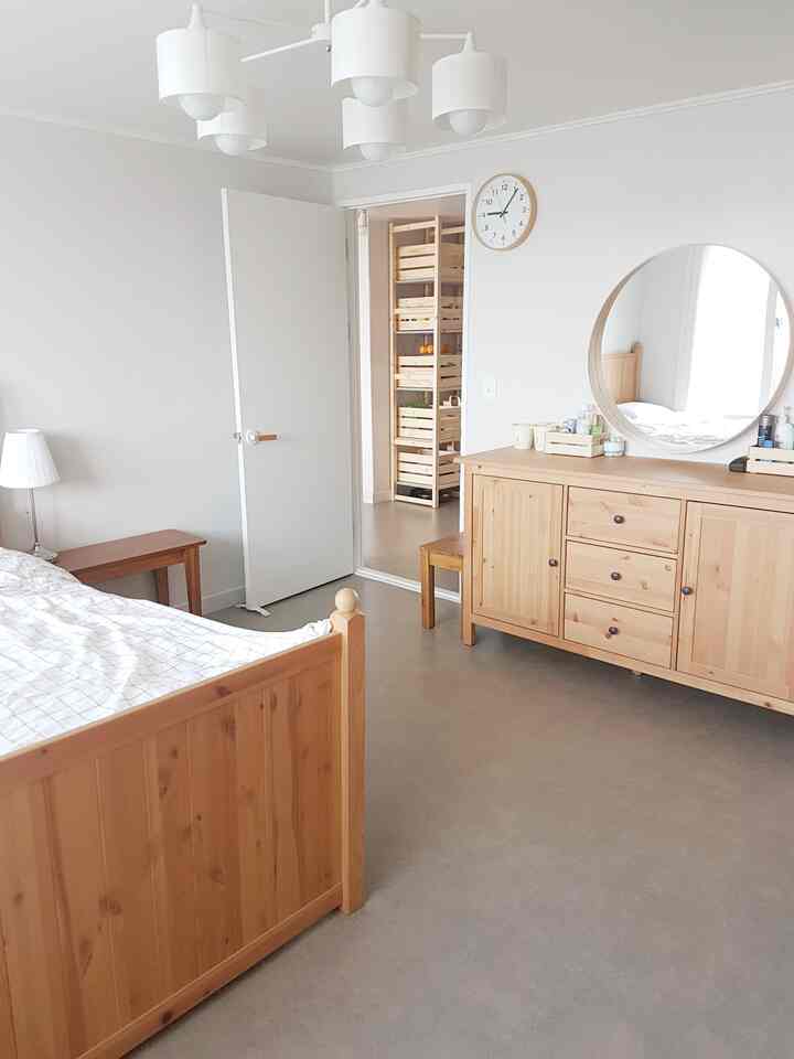 Bright white-toned bedroom featuring natural wood furniture with a cozy and comfortable atmosphere
