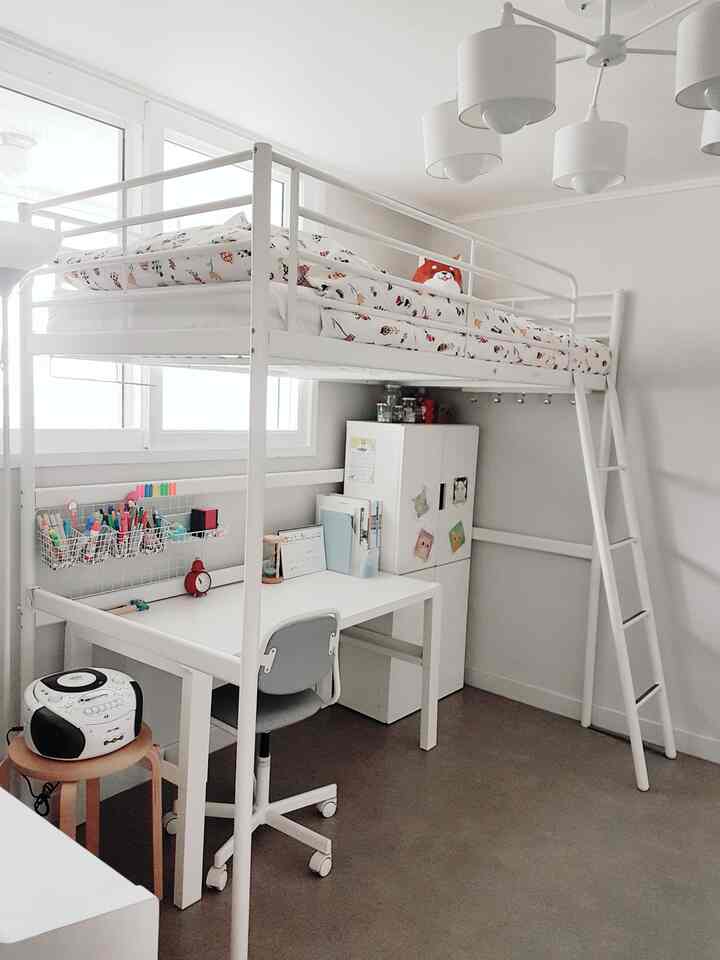 White-toned elementary kids' room featuring a loft bed, desk with organized stationery, and a clean, functional layout