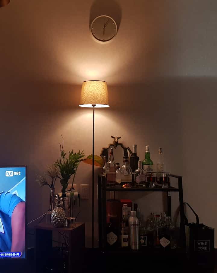 Cozy single household mini bar area with warm natural tone walls, featuring a floor lamp and wall clock complementing the ambiance
