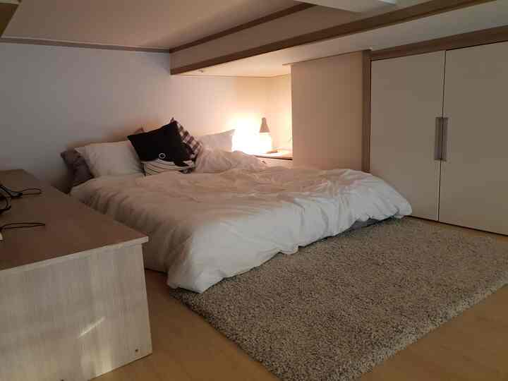 Natural tone bedroom featuring white bedding and beige rug with cozy ambiance
