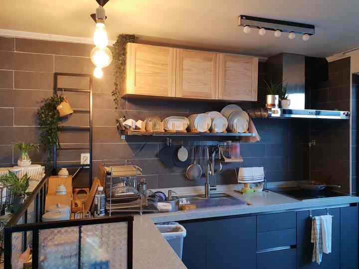 Modern kitchen space featuring black tiled walls, wood-tone upper cabinets, and white countertops