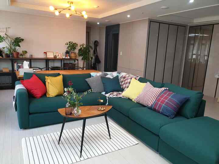 Natural tone 4-person living room featuring a large green sectional sofa and wood-tone coffee table