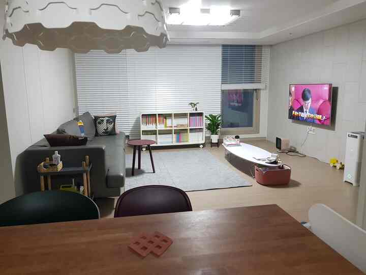 White and natural colored living room featuring a gray sofa, low coffee table and organized bookshelf creating a cozy atmosphere
