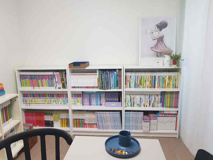 白とブラウンのトーンの子供部屋、大きな本棚と勉強机が配置された清潔感のある勉強空間