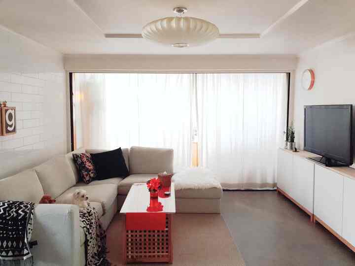 White and beige toned living room featuring a large sofa and curtains covering the veranda, creating a minimal atmosphere