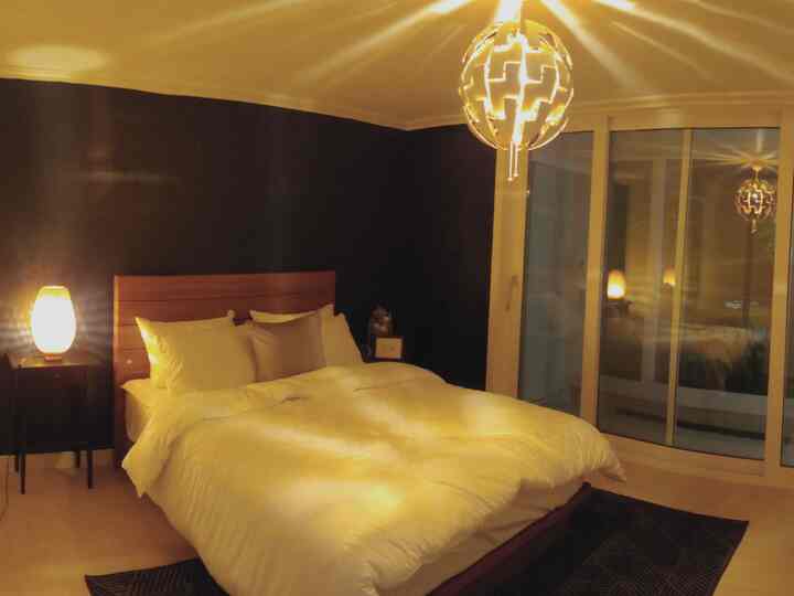 Cozy bedroom with navy accent wall, wood tone bed frame, warm lighting and curtains