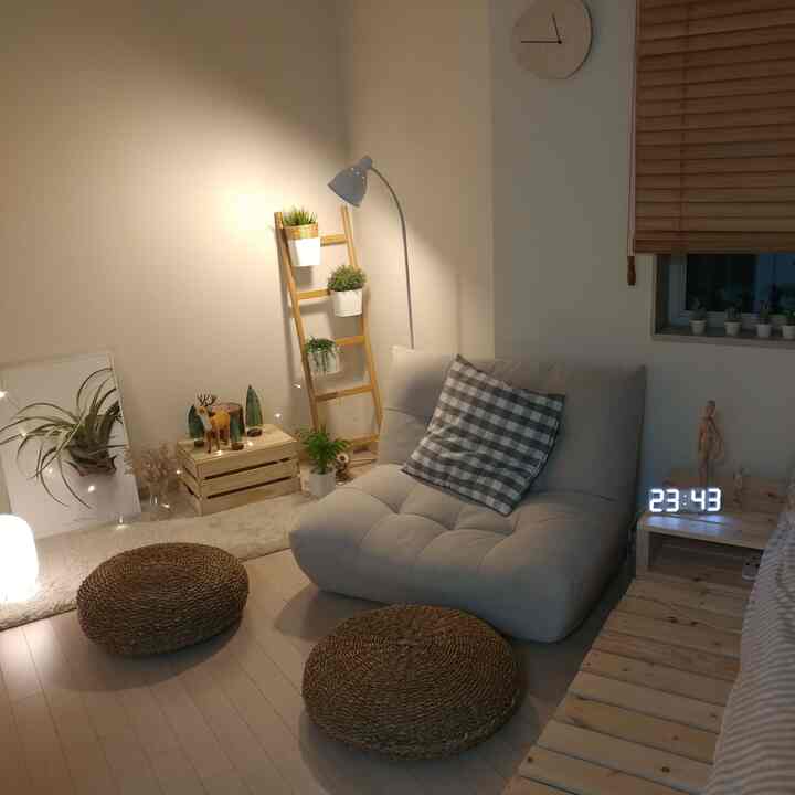 Natural wood tone studio living room featuring a gray floor sofa and warm lighting with string lights for a cozy atmosphere