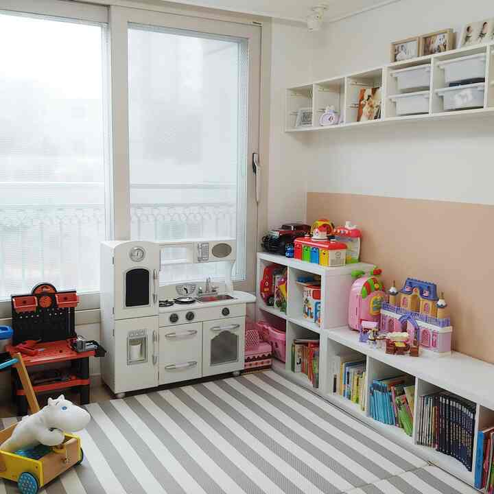 白とベージュの色調の子供部屋、子供用家具と玩具が配置された雰囲気ある遊び空間