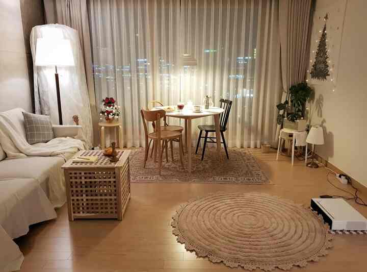 ナチュラルな色調のリビング、丸いダイニングテーブルと椅子、ソファとラグが調和した温かみのある照明空間