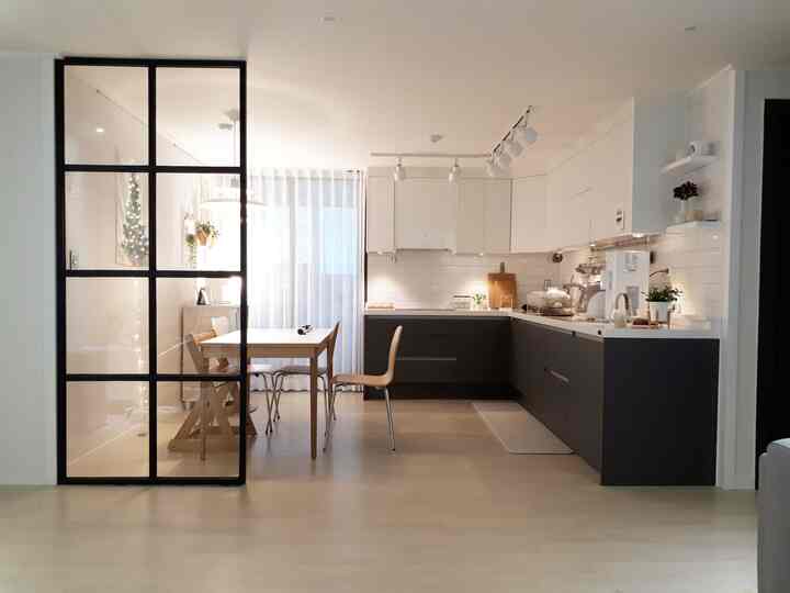 Modern kitchen in white and black tones with natural wood dining table and pendant lighting creating cafe style ambiance