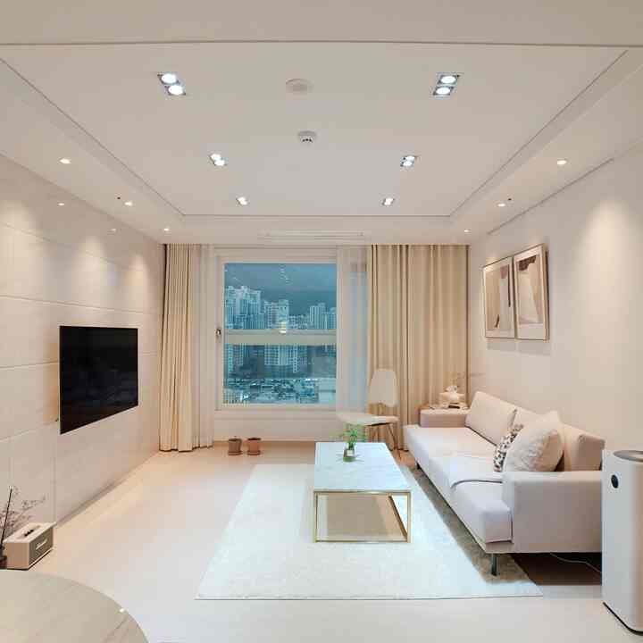 Minimalist living room in white and rose gold tones featuring large sofa and marble coffee table with clean atmosphere