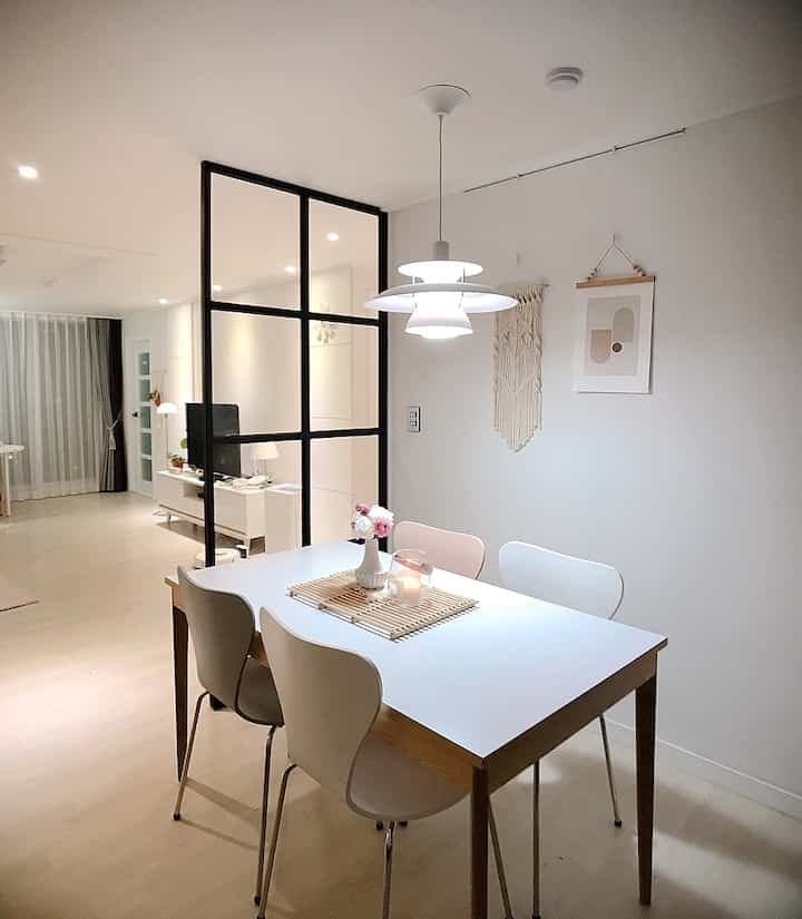 White and wood-toned kitchen dining room featuring a dining table and pendant light, creating a warm natural modern atmosphere