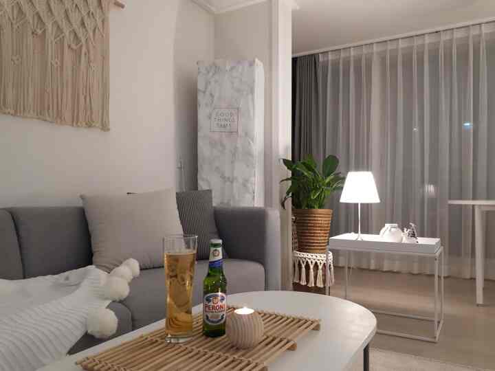 白とグレーの色調のリビング、グレーのソファとトレイ上のビールグラスが置かれた落ち着いた空間