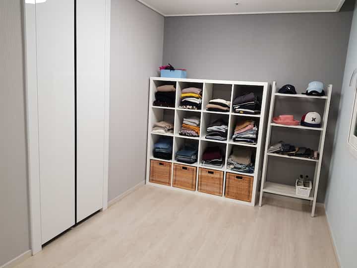 白とベージュのトーンの小さな部屋、整理された本棚とクローゼットが配置された清潔な空間