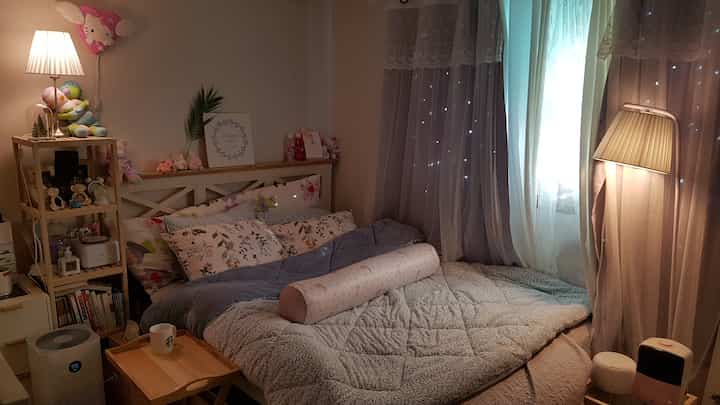 Warmly lit bedroom featuring natural tones, cozy bed and curtains creating a comfortable atmosphere.