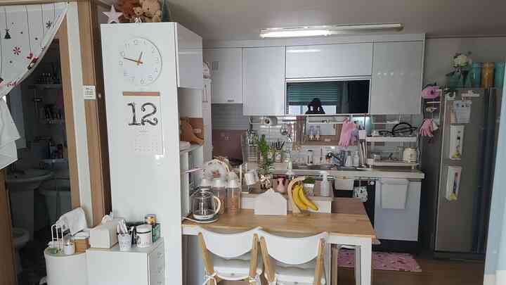 白と木目調が調和した狭いキッチン、ダイニングテーブルと収納アイデアが映える雰囲気のあるインテリア