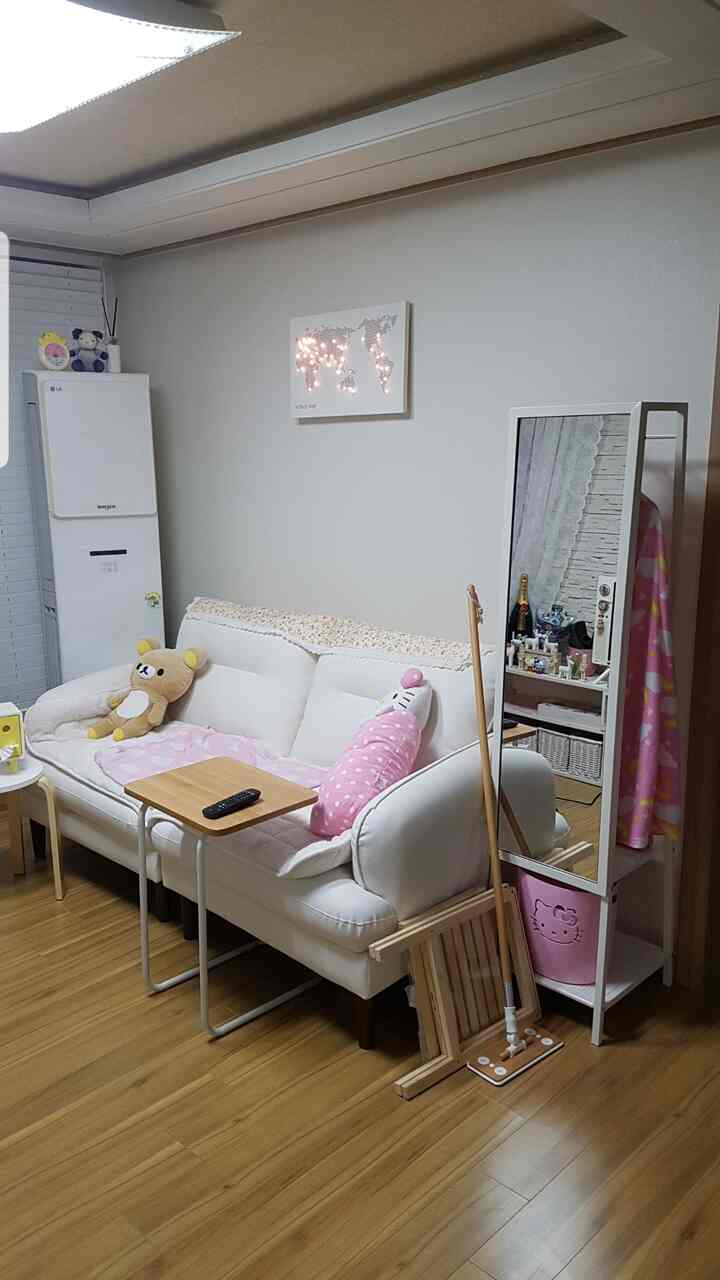 White and wood tone living room featuring a comfortable sofa, small stool, and standing mirror with a simple natural vibe
