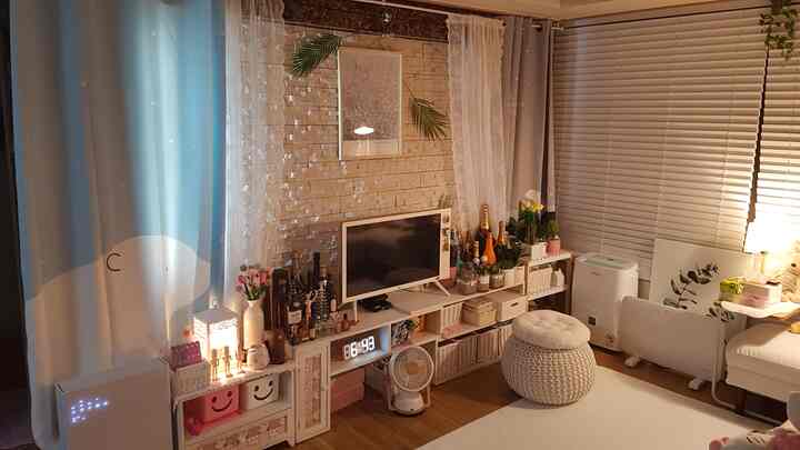 White and blue toned living room featuring a sofa and TV stand, creating a cozy and warm atmosphere