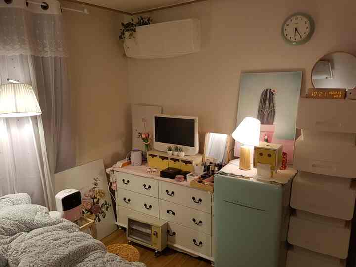 柔らかな木目調と白い家具が調和する落ち着いた寝室、ベッドとナイトテーブルが配置された快適な空間