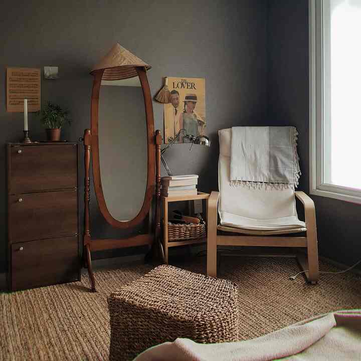 ナチュラルな色調の寝室、木製フレームのアームチェアと大きな木製のスタンドミラー、自然素材のカーペットが温かみのある雰囲気をつくるインテリア