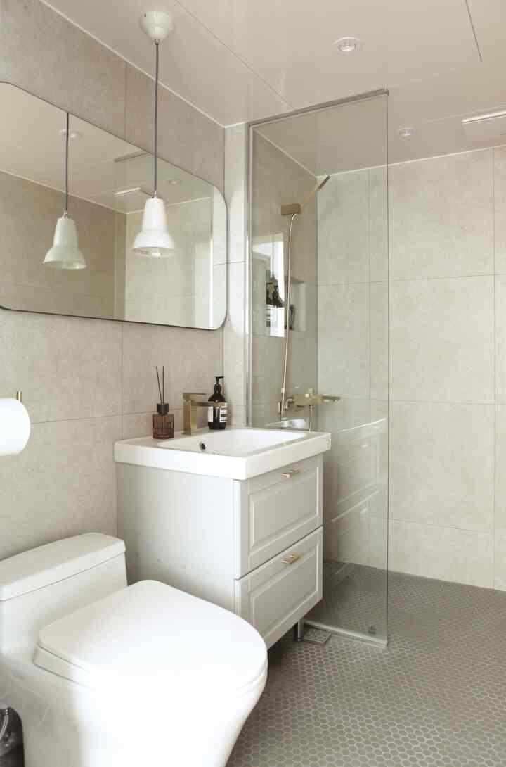 Light gray walls and floor in a modern restroom featuring a white toilet and double-drawer sink cabinet with a clean atmosphere