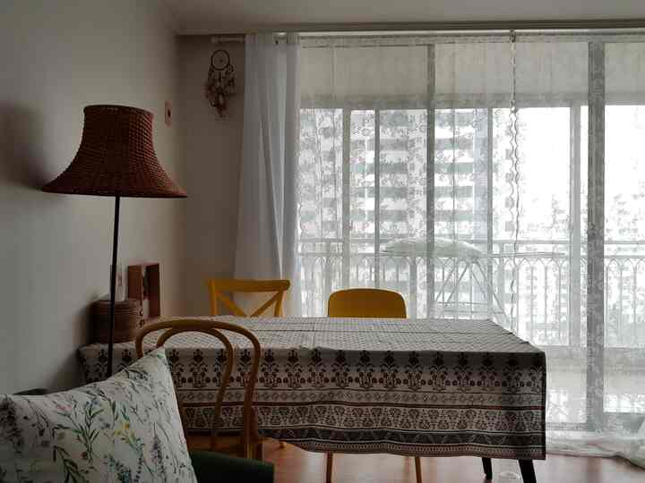 Natural tone living space featuring a dining table with Indian ethnic tablecloth near a veranda window with bright curtains