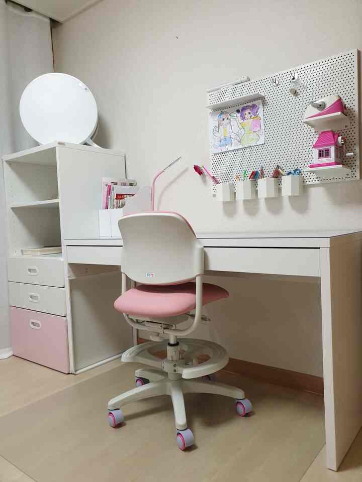 White and pink toned children's study area featuring a desk, chair, and pegboard storage with a neat and cozy vibe