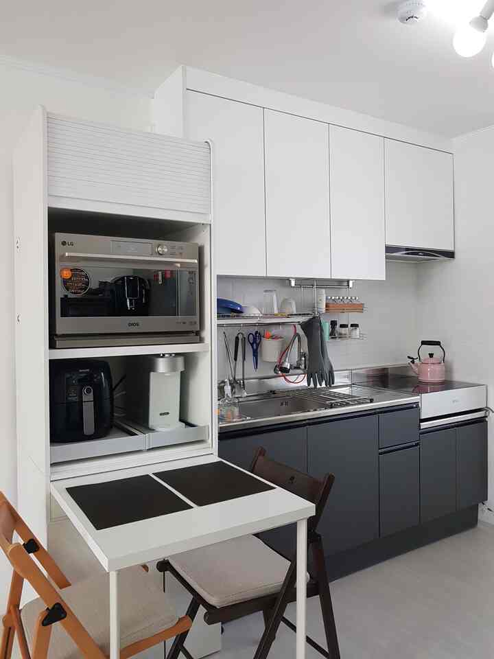 White and dark gray toned compact kitchen featuring small appliances and efficient storage solutions