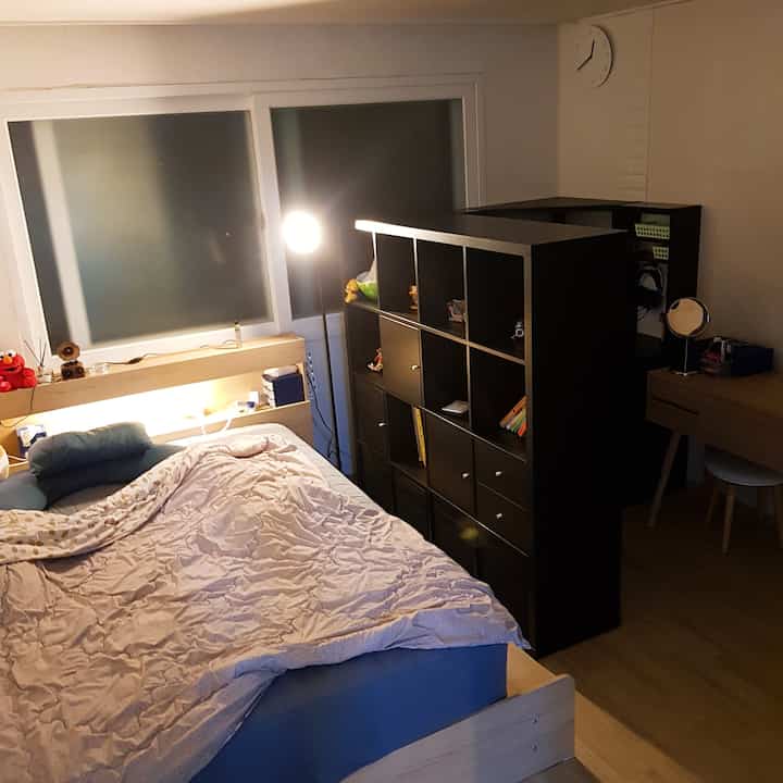 ナチュラルウッドと黒い棚が調和した、やわらかな照明の寝室空間