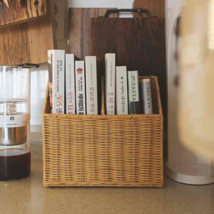 ナチュラルな色調のキッチンカウンターにラタン製の本棚が置かれ、料理本が整理された雰囲気のあるインテリア