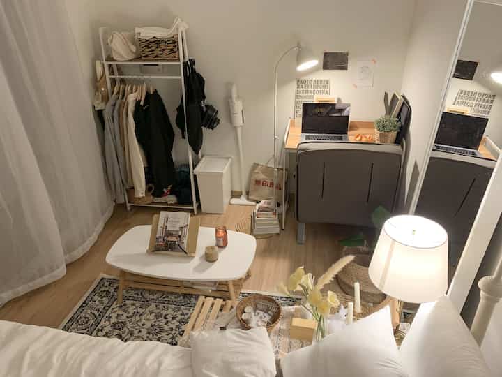 White and wood tone studio apartment featuring desk, sofa bed, and coffee table with cozy atmosphere